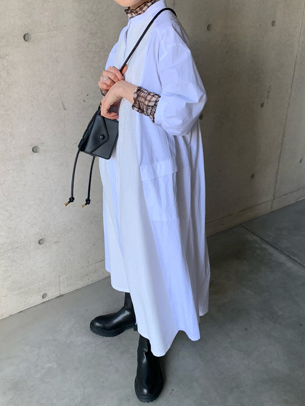 ホワイト系のシャツワンピース、ブラック系のブーツ、ブラウン系のTシャツ/カットソーを着用したレディースの冬コーディネートの3枚目の写真