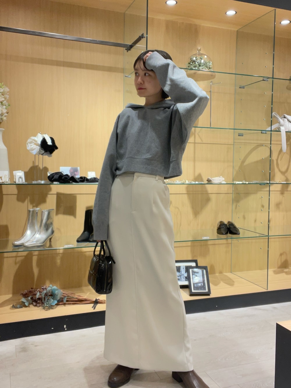 グレー系のパーカー、ホワイト系のスカート、ブラック系のバッグを着用したレディースの秋コーディネートの2枚目の写真