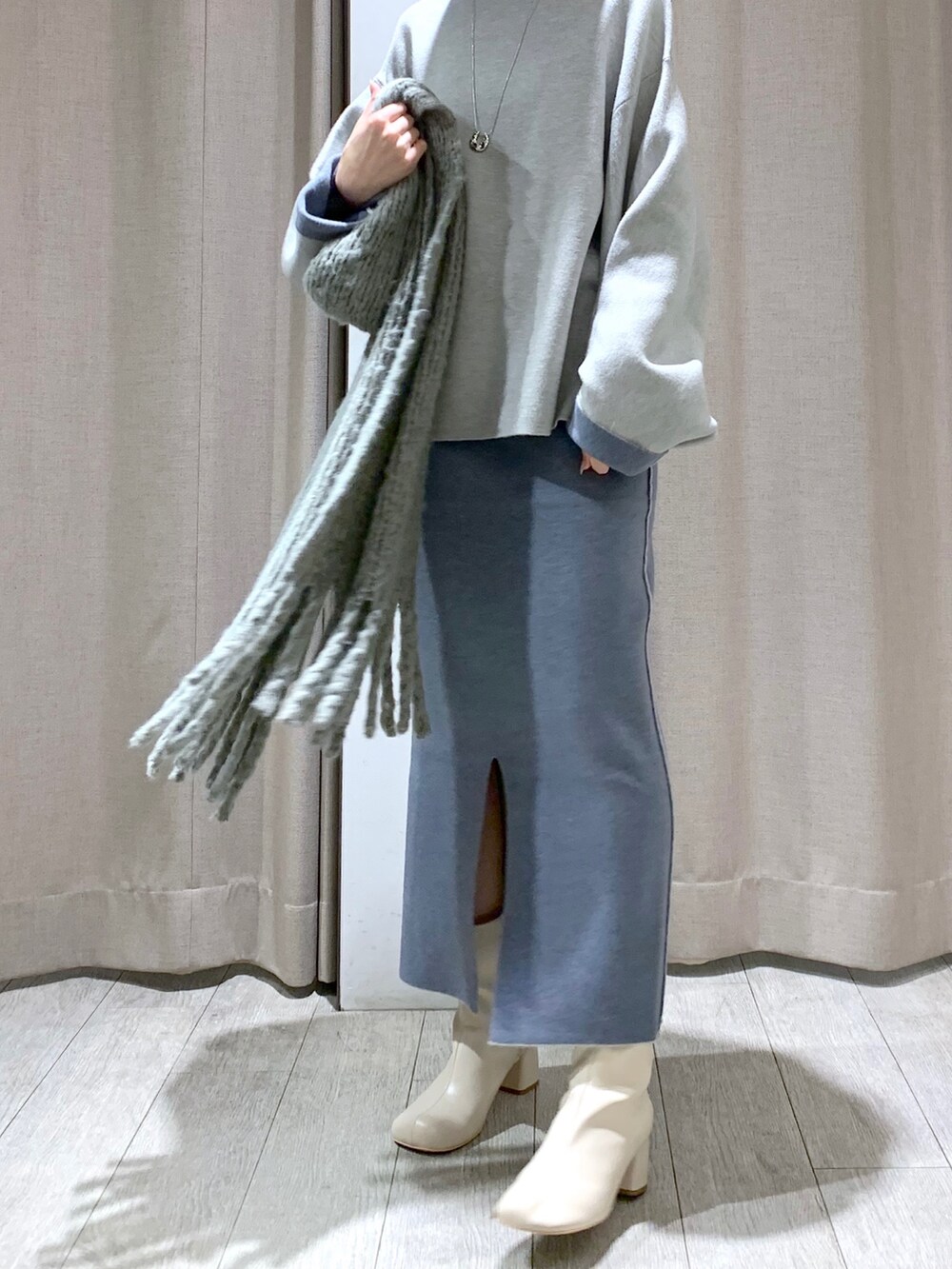 ホワイト系のブーツ、グレー系のニット/セーター、グレー系のスカートを着用したレディースの冬コーディネートの4枚目の写真