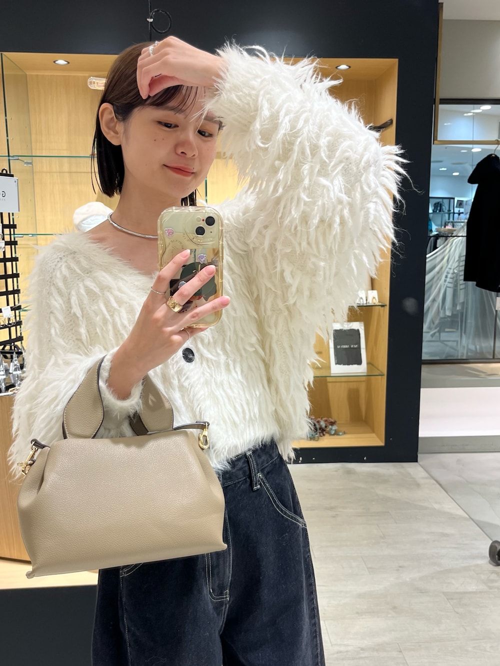 ホワイト系のカーディガン/ボレロ、ブラック系のデニムパンツ、ベージュ系のショルダーバッグを着用したレディースの秋コーディネートの5枚目の写真