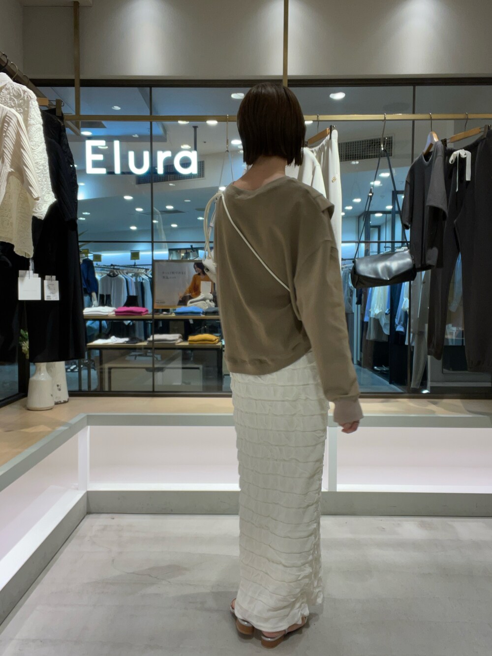 ブラウン系のTシャツ/カットソー、ホワイト系のスカート、シルバー系のサンダルを着用したレディースの秋コーディネートの3枚目の写真