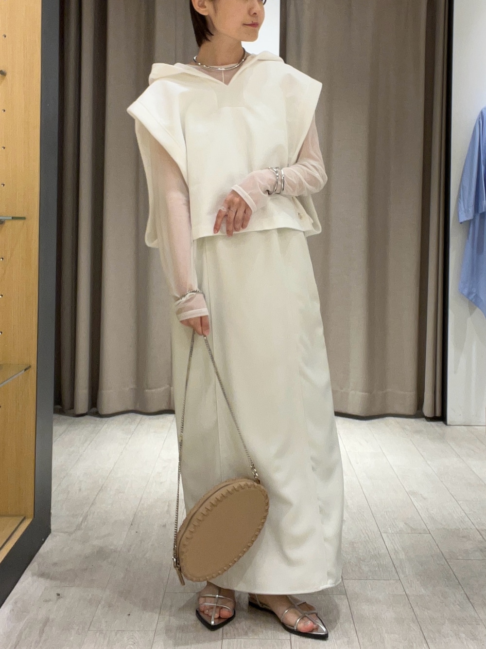 シルバー系のサンダル、ベージュ系のショルダーバッグ、ホワイト系のワンピースを着用したレディースの夏コーディネートの3枚目の写真