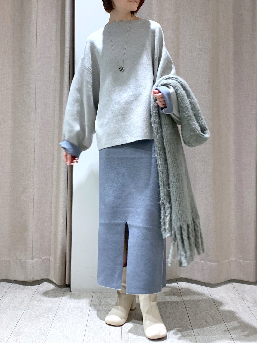 ホワイト系のブーツ、グレー系のニット/セーター、グレー系のスカートを着用したレディースの冬コーディネートの3枚目の写真