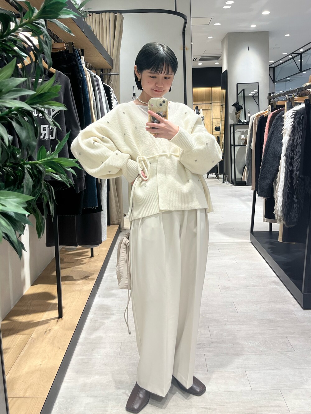 ホワイト系のカーディガン/ボレロ、ホワイト系のバッグ、ブラウン系のブーツを着用したレディースの冬コーディネートの2枚目の写真