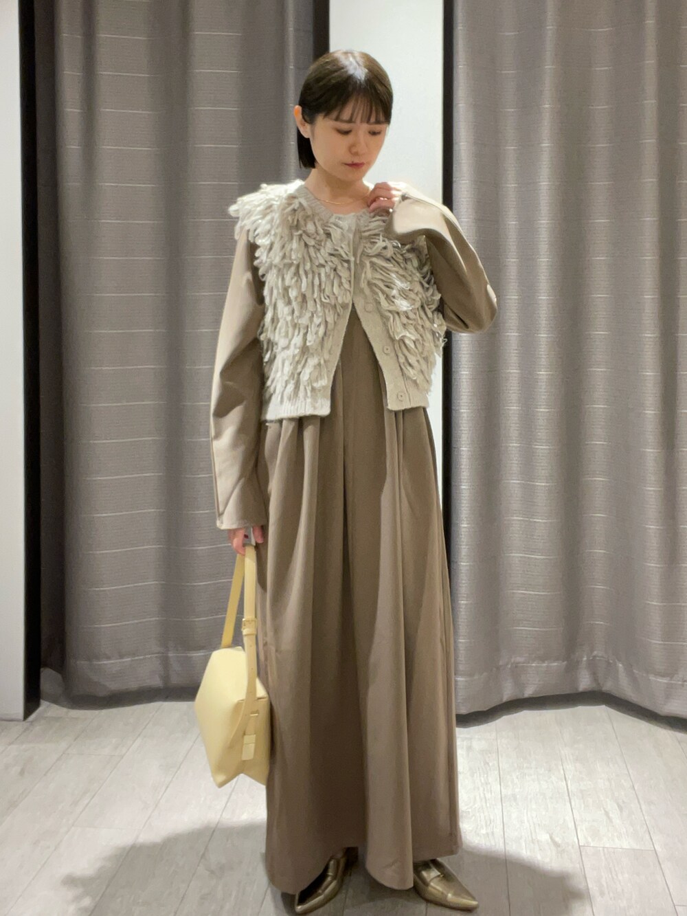 ベージュ系のショルダーバッグ、ゴールド系のパンプス、ブラウン系のワンピースを着用したレディースの秋コーディネートの5枚目の写真