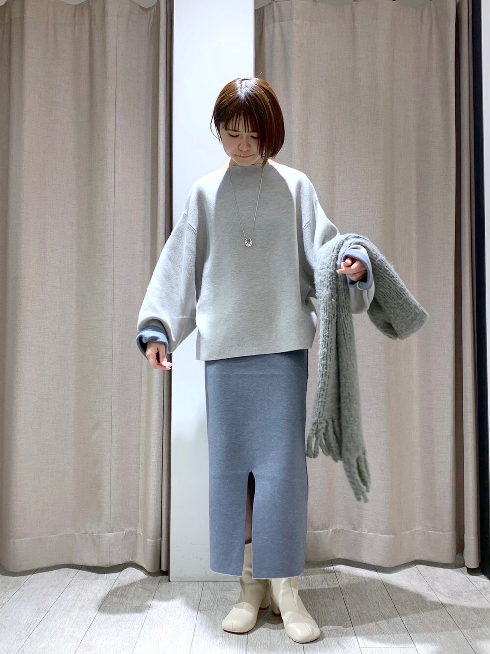 ホワイト系のブーツ、グレー系のニット/セーター、グレー系のスカートを着用したレディースの冬コーディネートの2枚目の写真