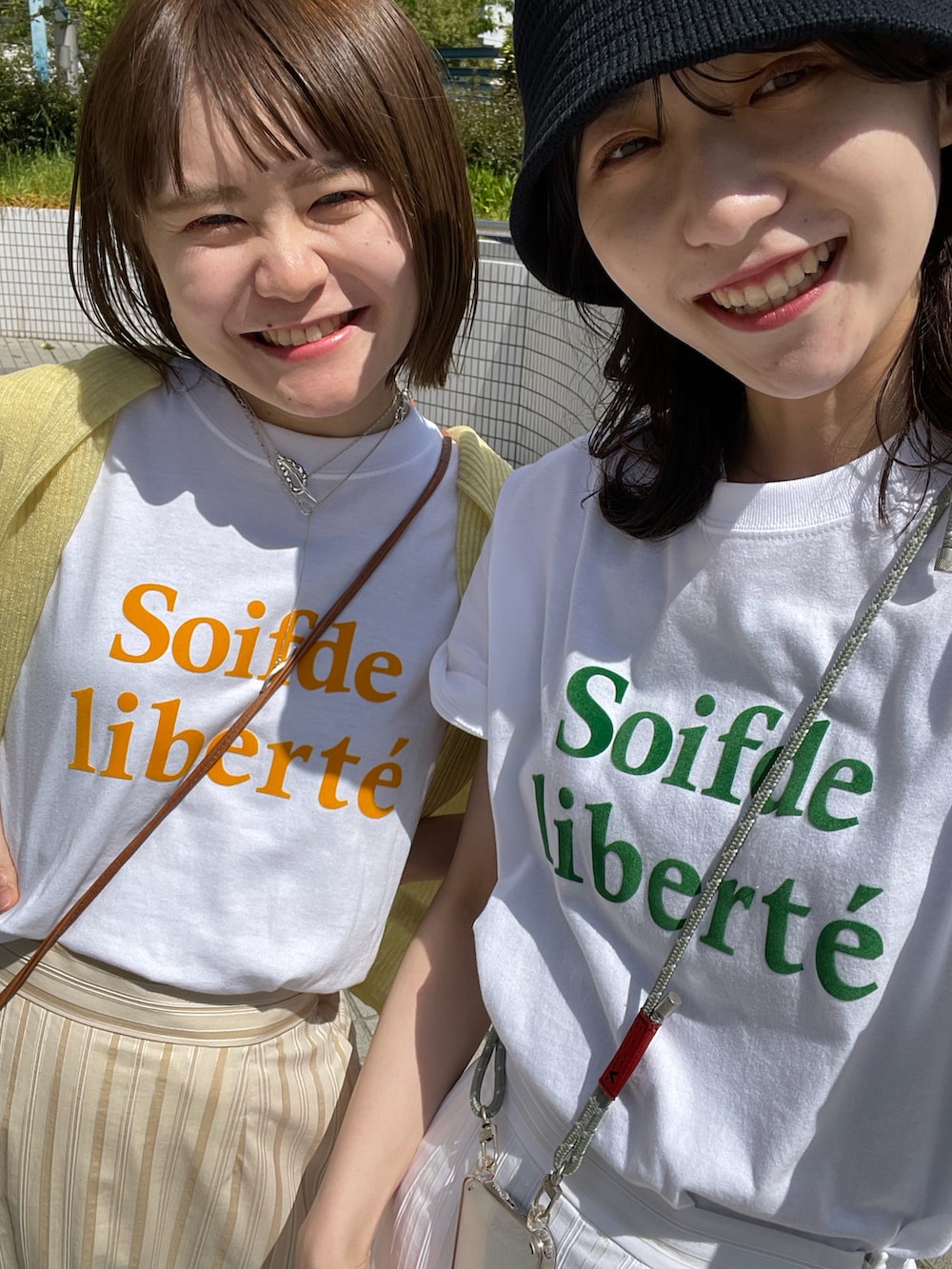 ベージュ系のスカート、オレンジ系のTシャツ/カットソー、イエロー系のニット/セーターを着用したレディースの春コーディネートの5枚目の写真