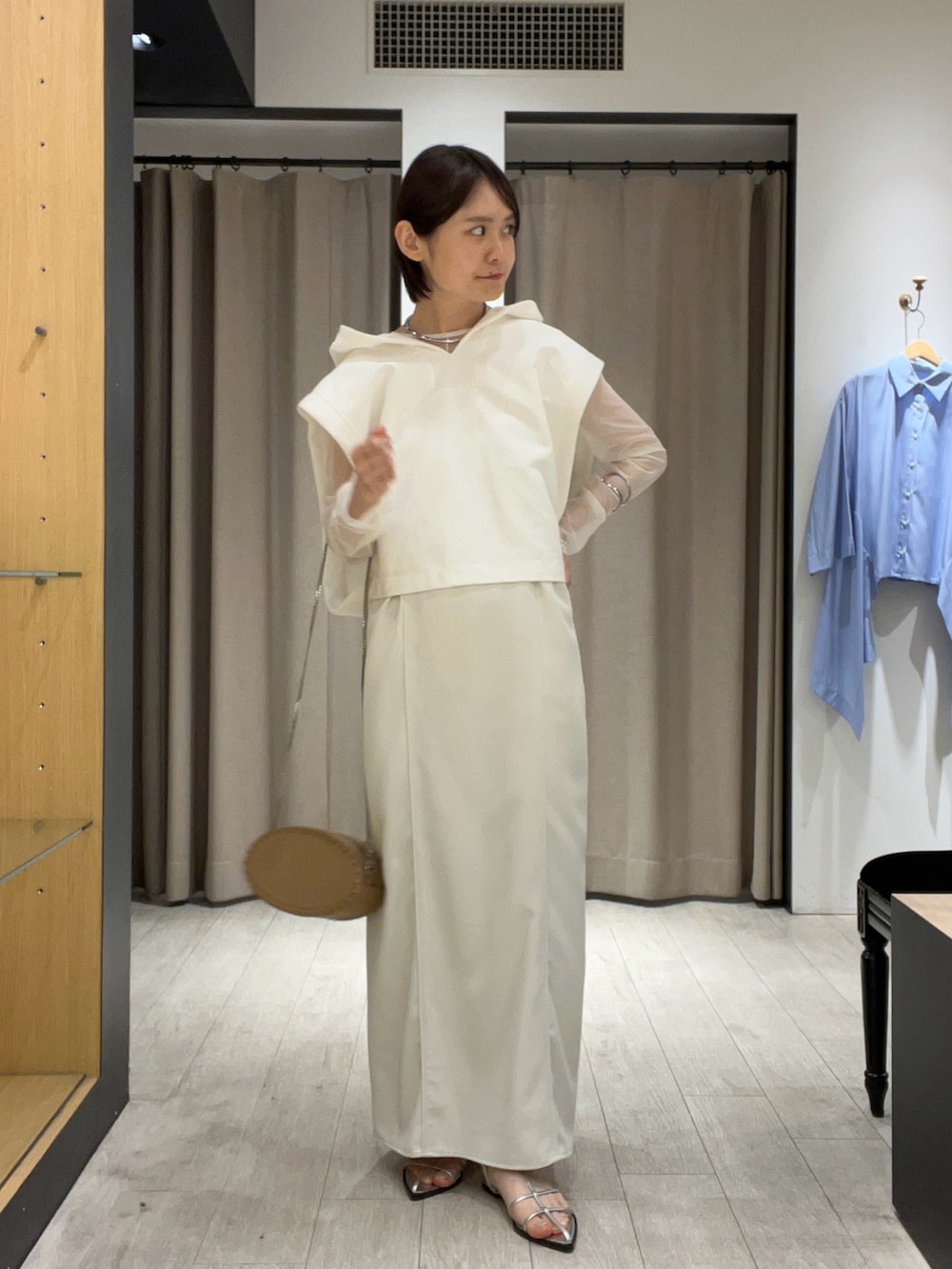 シルバー系のサンダル、ベージュ系のショルダーバッグ、ホワイト系のワンピースを着用したレディースの夏コーディネートの2枚目の写真