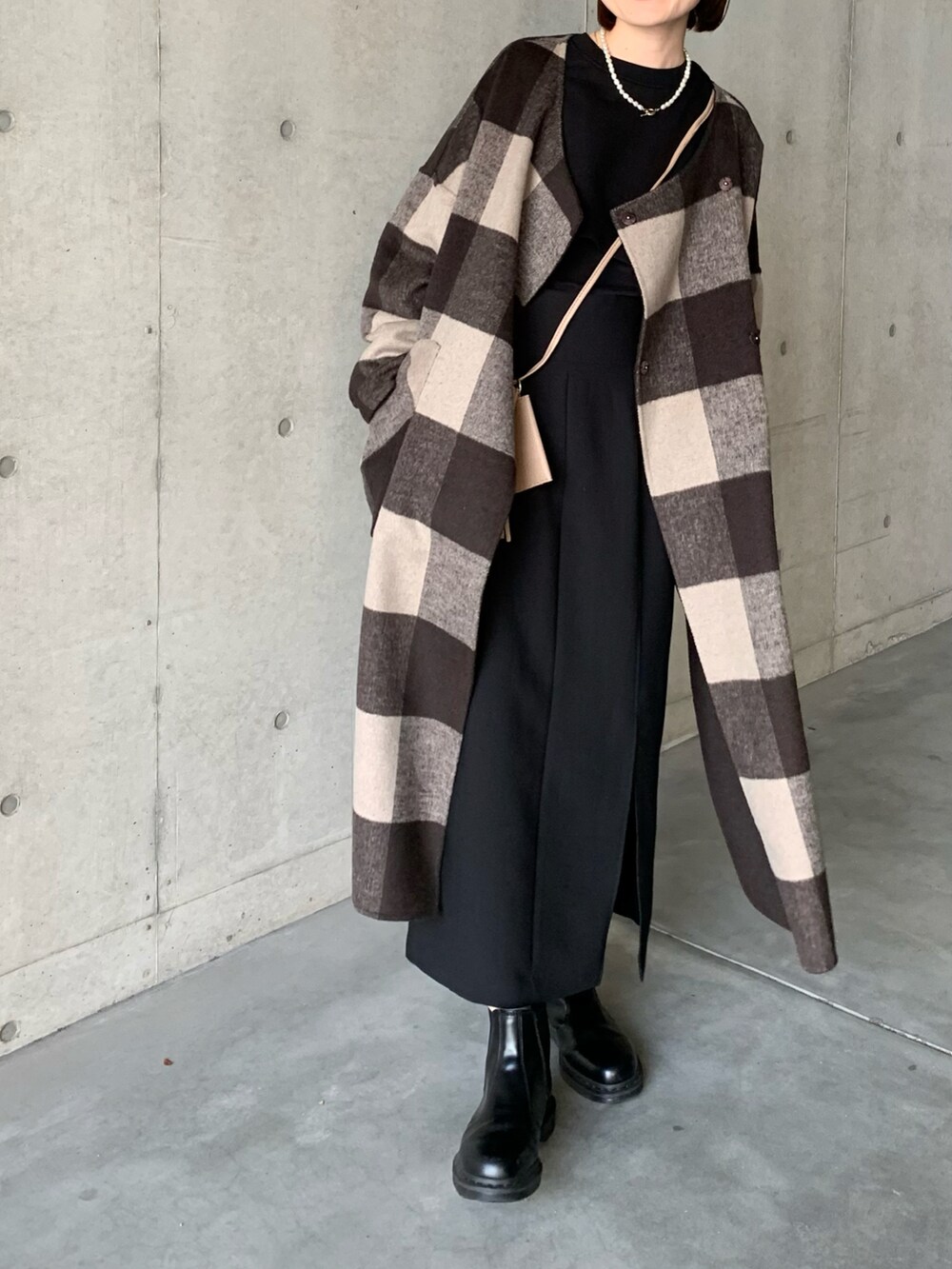 ブラック系のブーツ、ブラウン系のノーカラーコート、ブラック系のスカートを着用したレディースの秋コーディネートの3枚目の写真