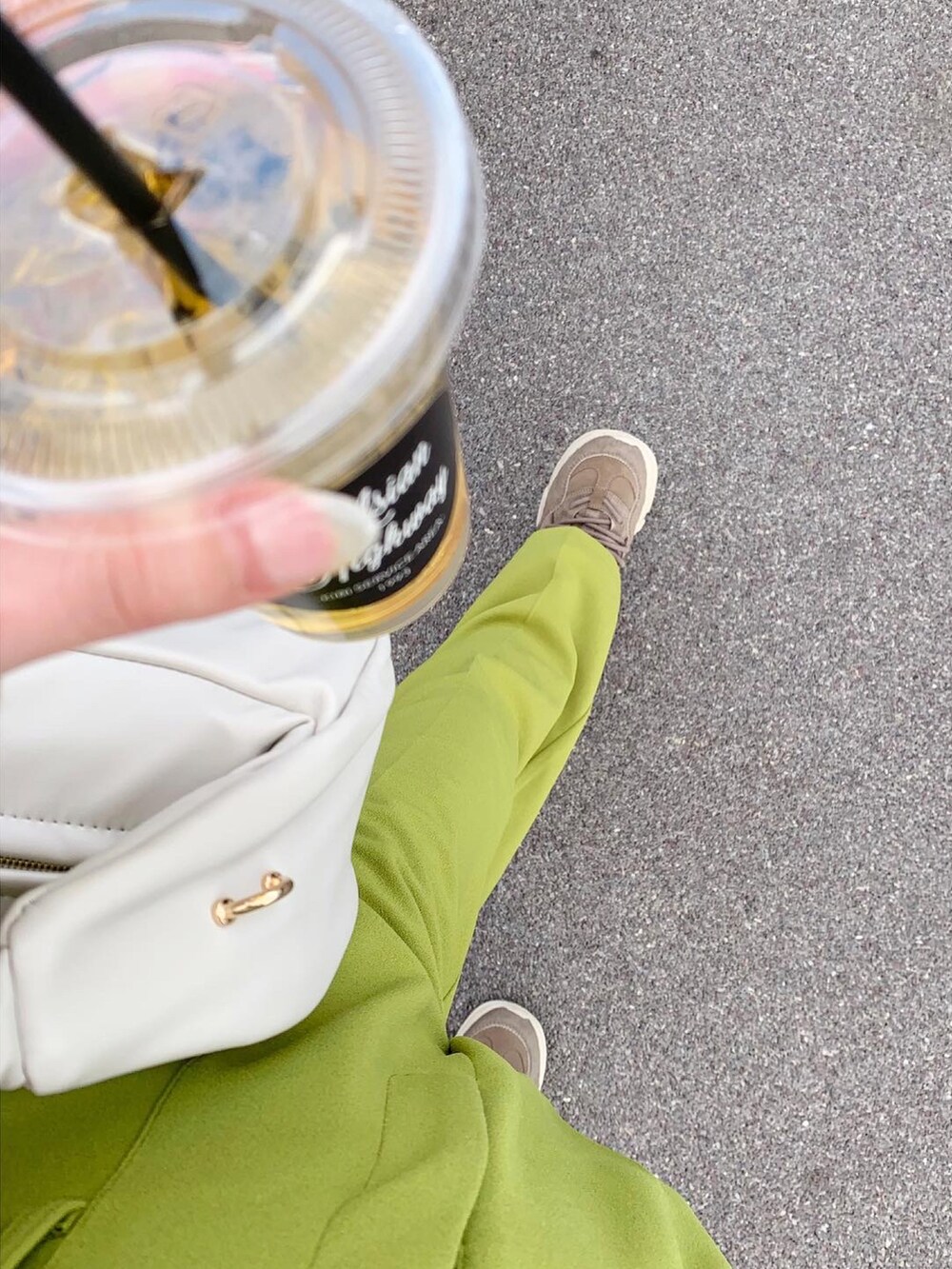 グリーン系のスラックス、ベージュ系のスニーカー、ホワイト系のハンドバッグを着用したレディースの冬コーディネートの5枚目の写真