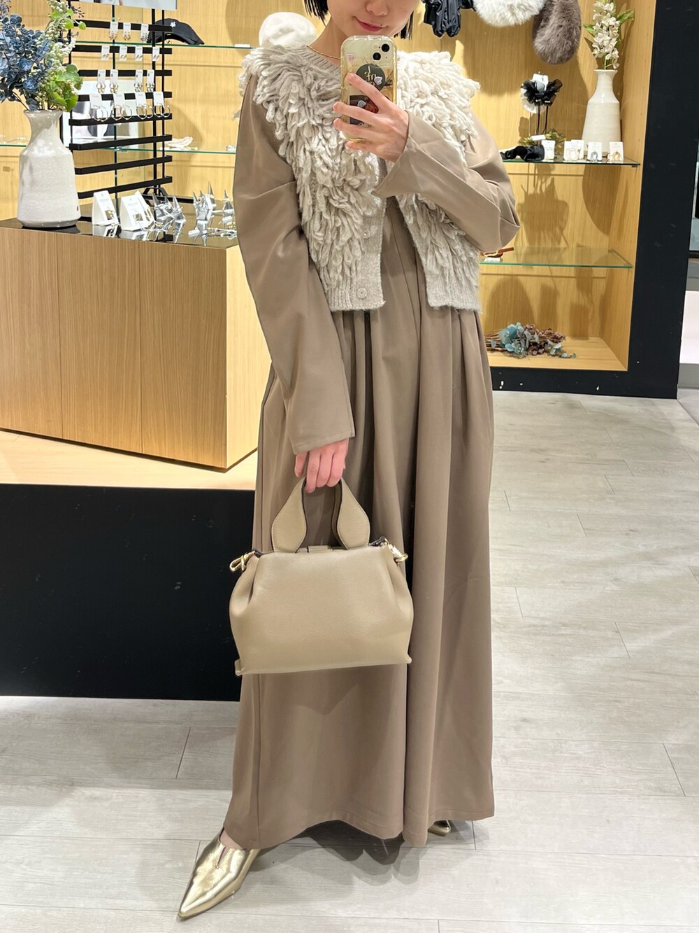 ベージュ系のショルダーバッグ、ゴールド系のパンプス、ブラウン系のワンピースを着用したレディースの秋コーディネートの3枚目の写真