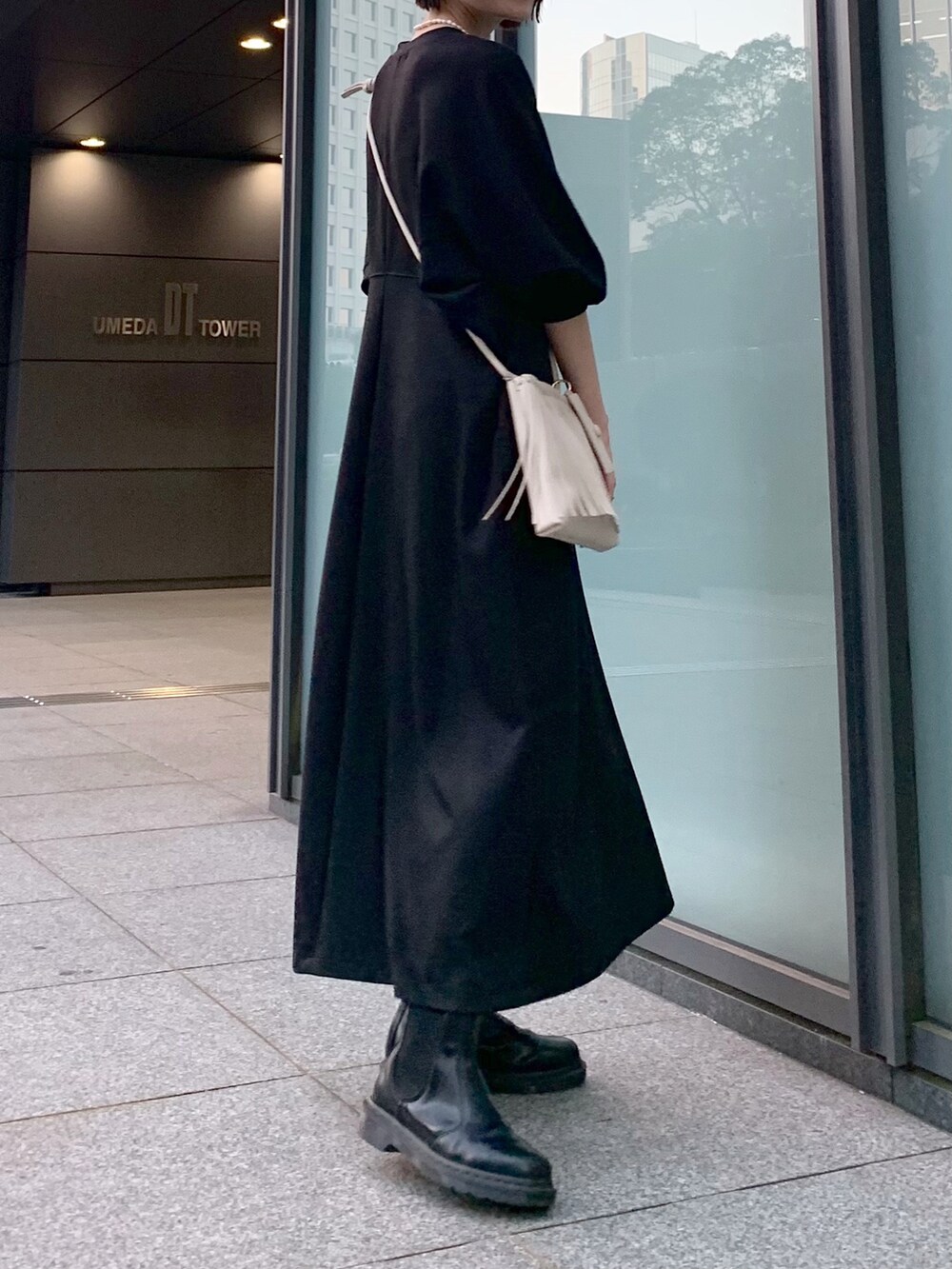 ブラック系のワンピース、ホワイト系のショルダーバッグ、ブラック系のブーツを着用したレディースの冬コーディネートの3枚目の写真