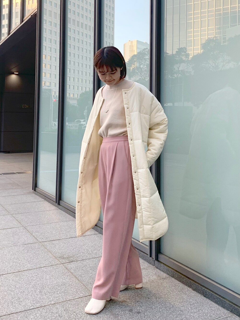 ピンク系のその他パンツ、ベージュ系のニット/セーター、ホワイト系のノーカラーコートを着用したレディースの冬コーディネートの2枚目の写真
