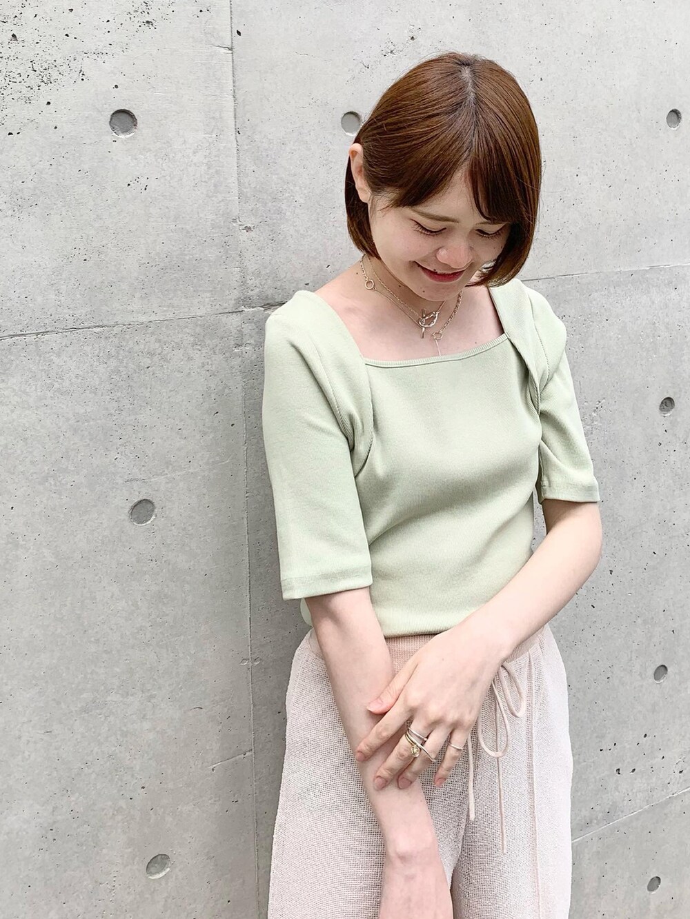 ホワイト系のサンダル、ベージュ系のハンドバッグ、グリーン系のTシャツ/カットソーを着用したレディースの春コーディネートの2枚目の写真