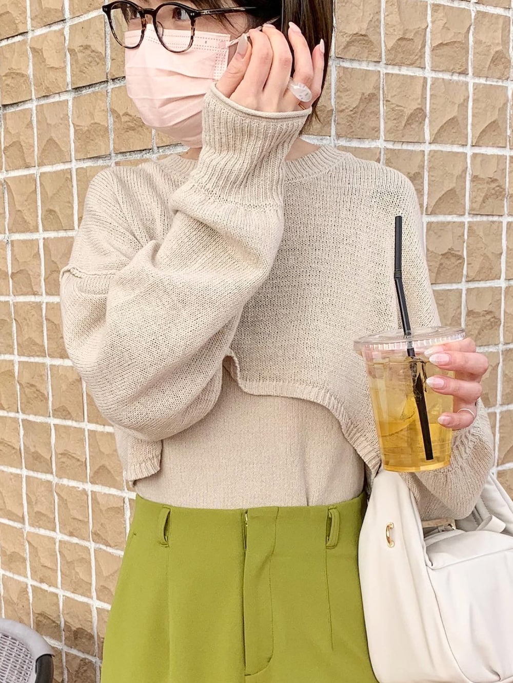 グリーン系のスラックス、ベージュ系のスニーカー、ホワイト系のハンドバッグを着用したレディースの冬コーディネートの4枚目の写真