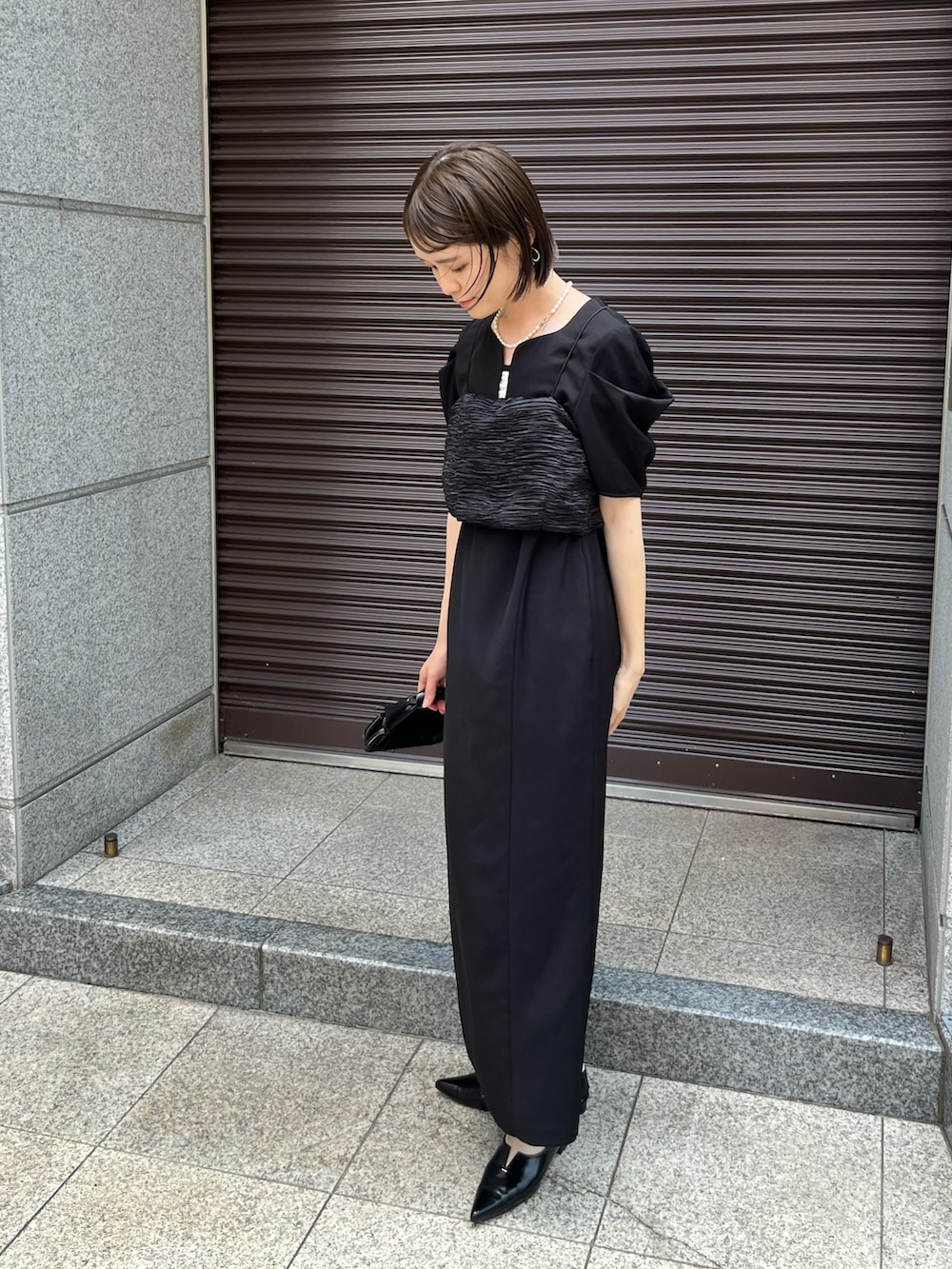 ブラック系のワンピース、ブラック系のパンプス、ブラック系のバッグを着用したレディースの夏コーディネートの4枚目の写真