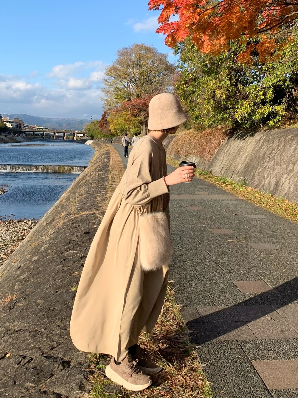 ベージュ系のスニーカー、ベージュ系のワンピース、ベージュ系のショルダーバッグを着用したレディースの秋コーディネートの3枚目の写真