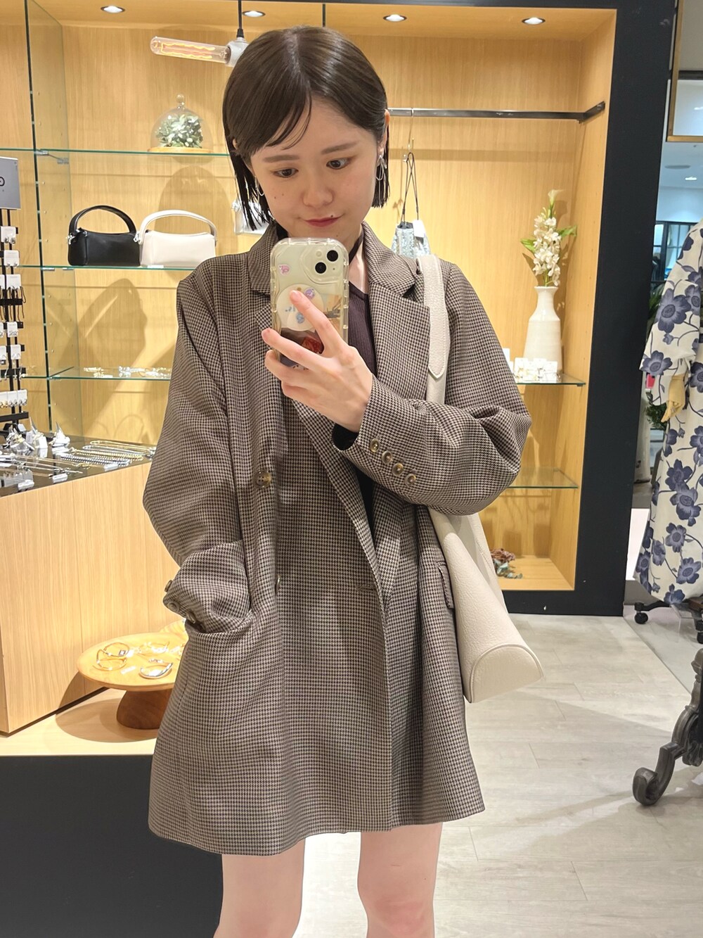 ブラウン系のテーラードジャケット、ブラウン系のニット/セーター、ホワイト系のトートバッグを着用したレディースの夏コーディネートの2枚目の写真