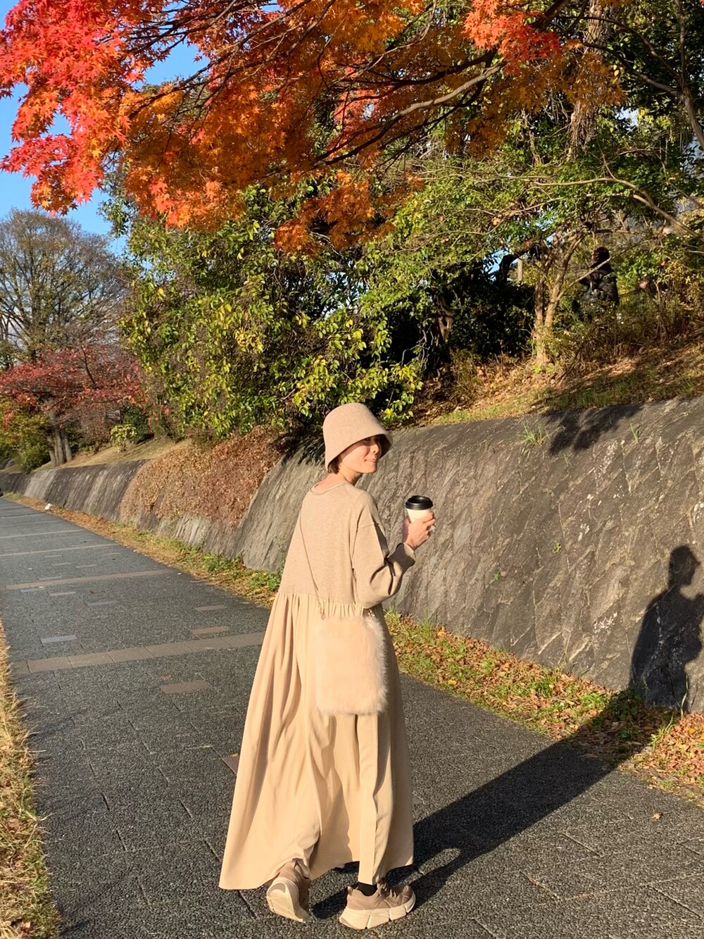ベージュ系のスニーカー、ベージュ系のワンピース、ベージュ系のショルダーバッグを着用したレディースの秋コーディネートの2枚目の写真