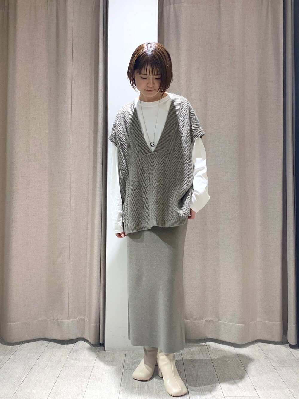 ベージュ系のワンピース、ホワイト系のブーツ、シルバー系のネックレスを着用したレディースの冬コーディネートの3枚目の写真