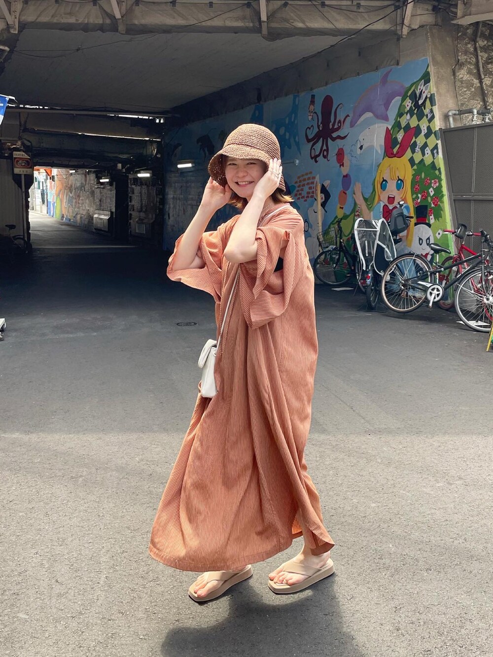 オレンジ系のワンピース、ホワイト系のショルダーバッグ、ベージュ系のサンダルを着用したレディースの夏コーディネートの5枚目の写真