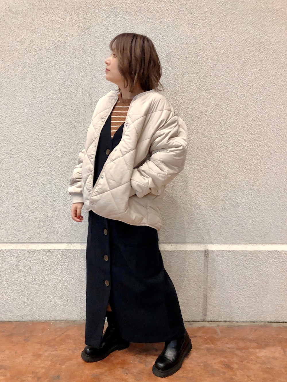 ブラック系のワンピース、イエロー系のニット/セーター、ベージュ系のノーカラーコートを着用したレディースの冬コーディネートの2枚目の写真