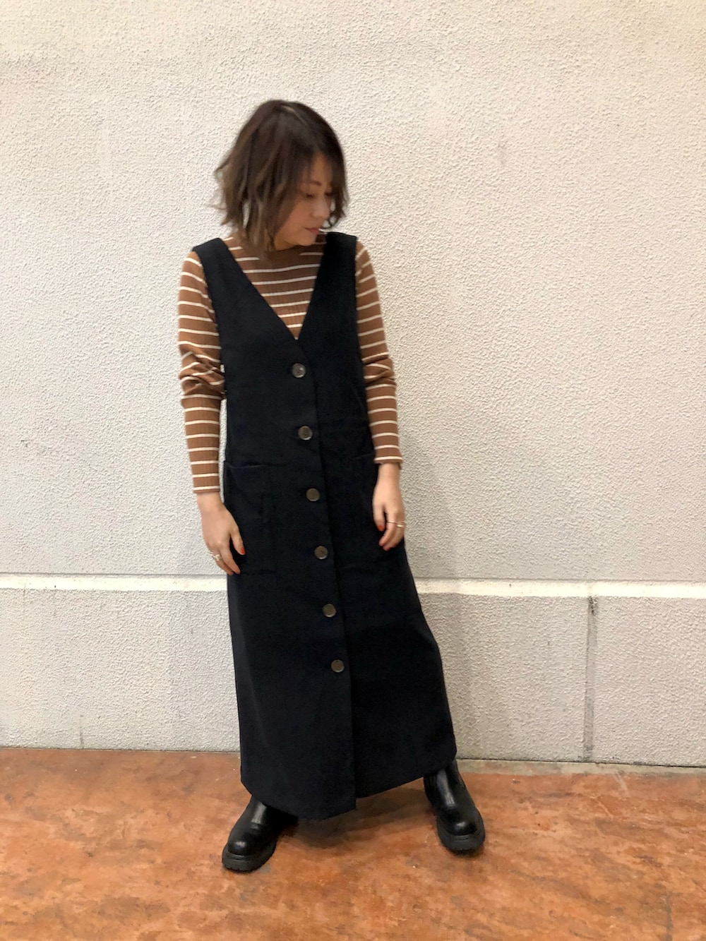 ブラック系のワンピース、イエロー系のニット/セーター、ベージュ系のノーカラーコートを着用したレディースの冬コーディネートの3枚目の写真