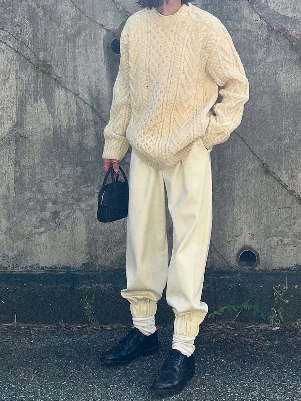 ホワイト系のパンツ、ブラック系のドレスシューズ、ブラック系のボストンバッグを着用したレディースの秋コーディネートの2枚目の写真