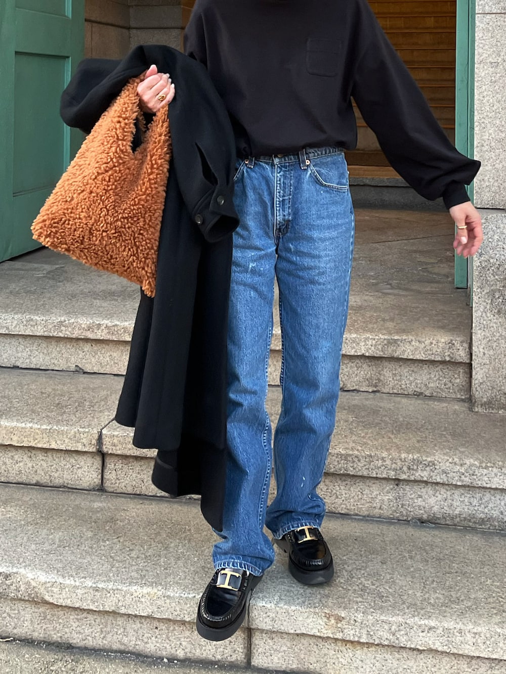 ブラウン系のハンドバッグ、ブラック系のローファーを着用したレディースの冬コーディネートの2枚目の写真