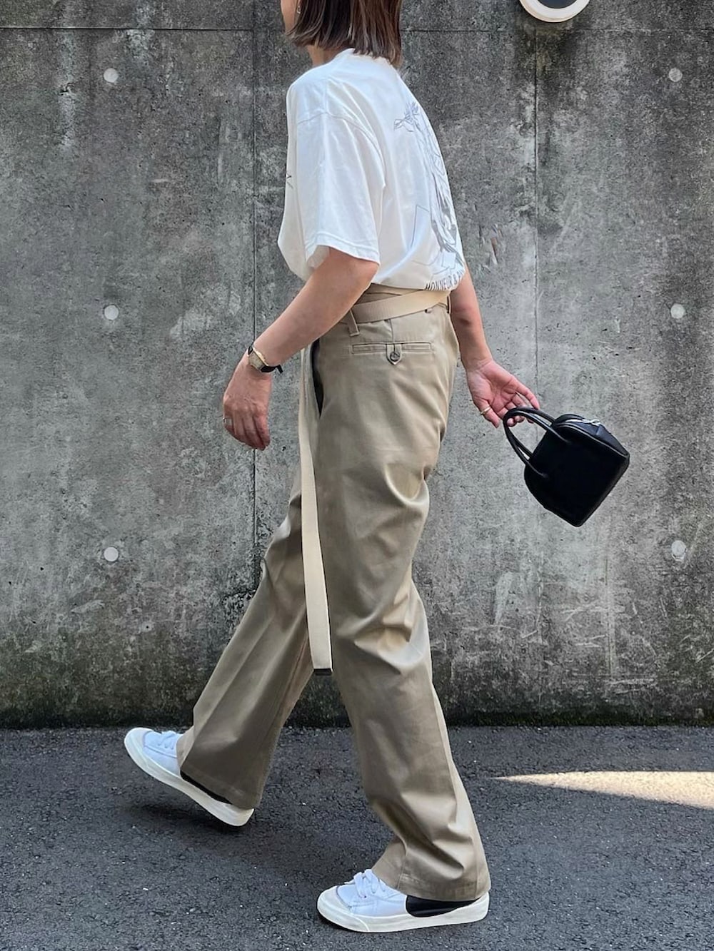 ベージュ系のその他パンツ、ブラック系のボストンバッグ、ホワイト系のスニーカーを着用したレディースの夏コーディネートの3枚目の写真