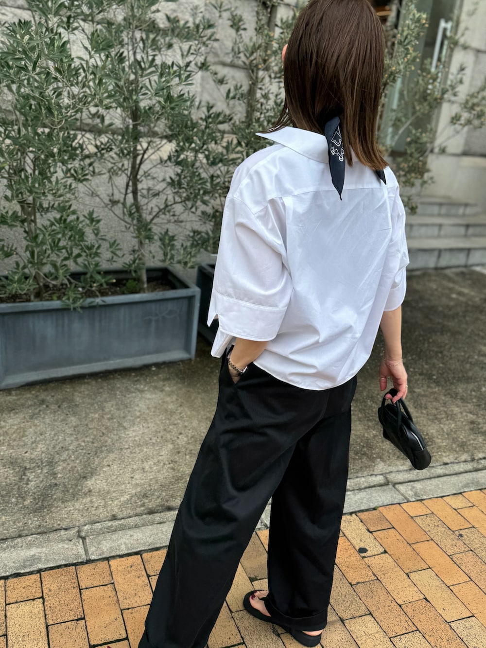 ホワイト系のシャツ/ブラウス、ブラック系のチノパンツ、シルバー系のブレスレットを着用したレディースの夏コーディネートの2枚目の写真