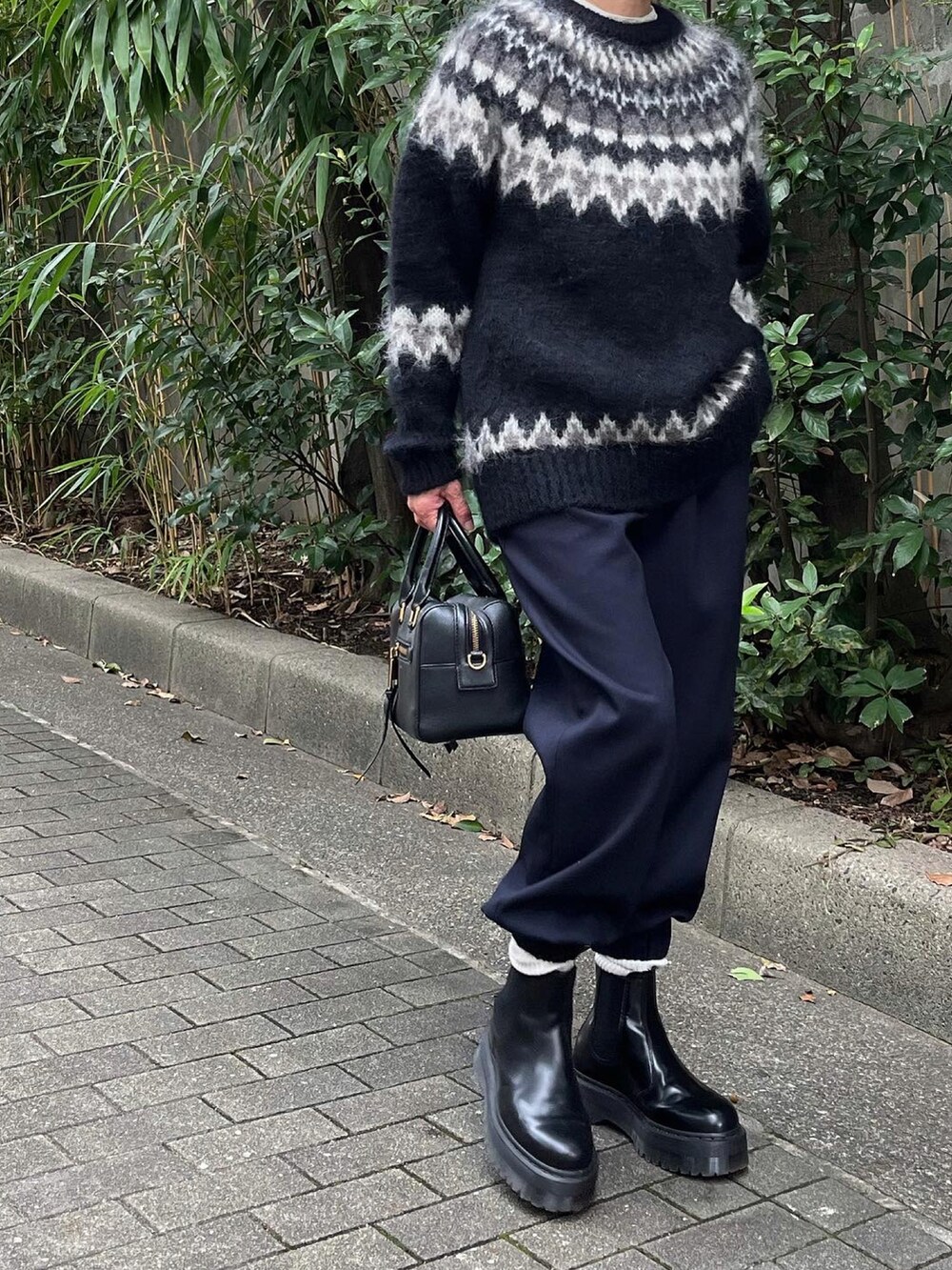 ブラック系のニット/セーター、ブルー系のスラックスを着用したレディースの秋コーディネートの2枚目の写真
