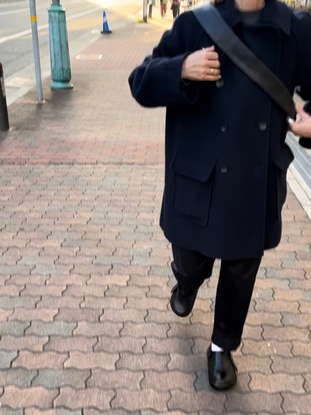 ブルー系のピーコート、ブラック系のパンツ、ブラック系のショルダーバッグを着用したレディースの秋コーディネートの3枚目の写真