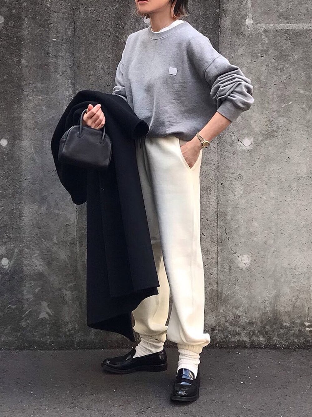 グレー系のスウェット、ホワイト系のスウェットパンツ、ブラック系のボストンバッグを着用したレディースの冬コーディネートの2枚目の写真