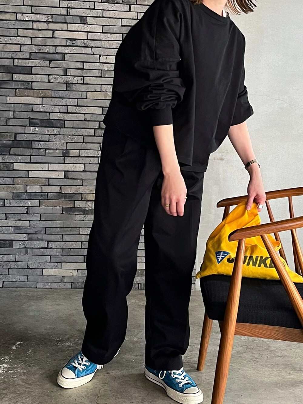 ブラック系のチノパンツ、ブルー系のスニーカー、シルバー系のピアス（両耳用）を着用したレディースの春コーディネートの2枚目の写真