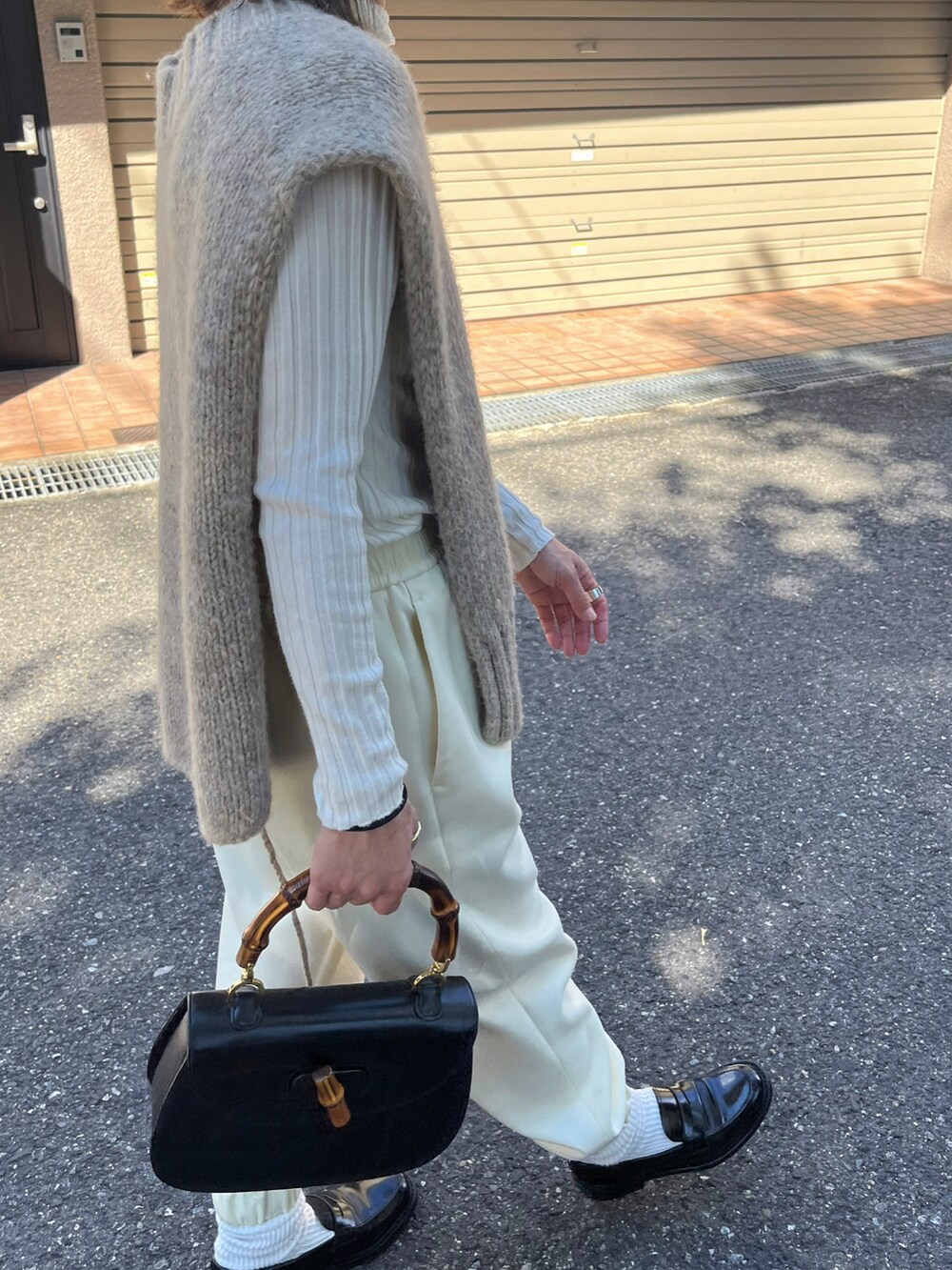 ホワイト系のパンツ、ブラック系のローファー、ブラウン系のストール/ショールを着用したレディースの秋コーディネートの3枚目の写真