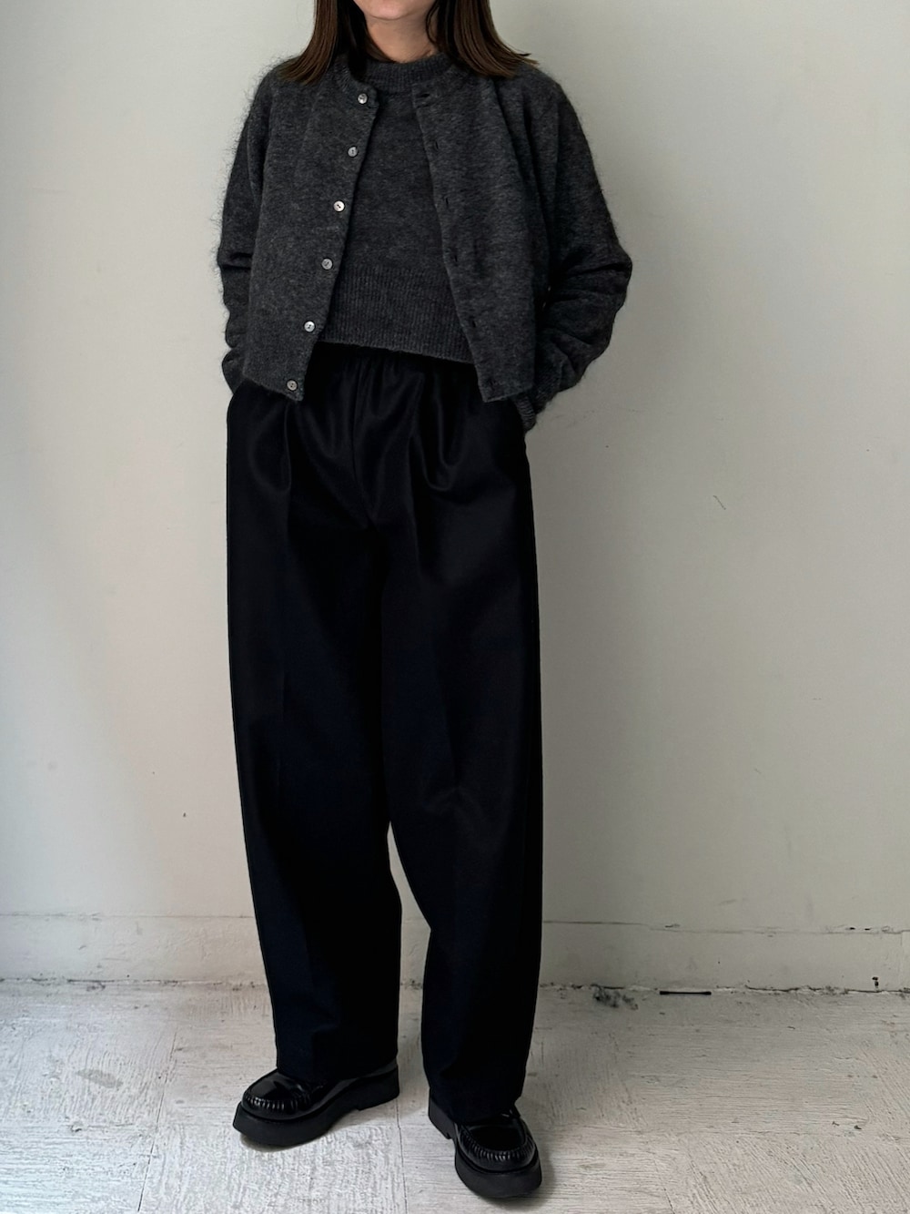 ブラック系のテーラードジャケット、ブラック系のスラックス、グレー系のカーディガン/ボレロを着用したレディースの秋コーディネートの2枚目の写真