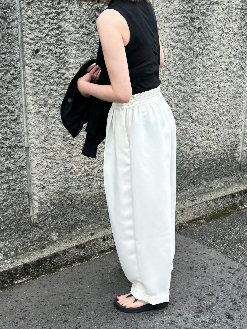 ブラック系のTシャツ/カットソー、ホワイト系のパンツ、ブラック系のサンダルを着用したレディースの春コーディネートの4枚目の写真