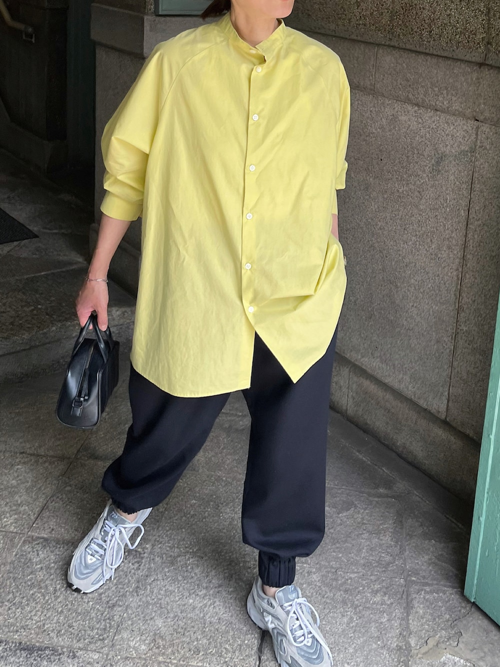 イエロー系のシャツ/ブラウス、ブルー系のスラックス、グレー系のスニーカーを着用したレディースの夏コーディネートの3枚目の写真