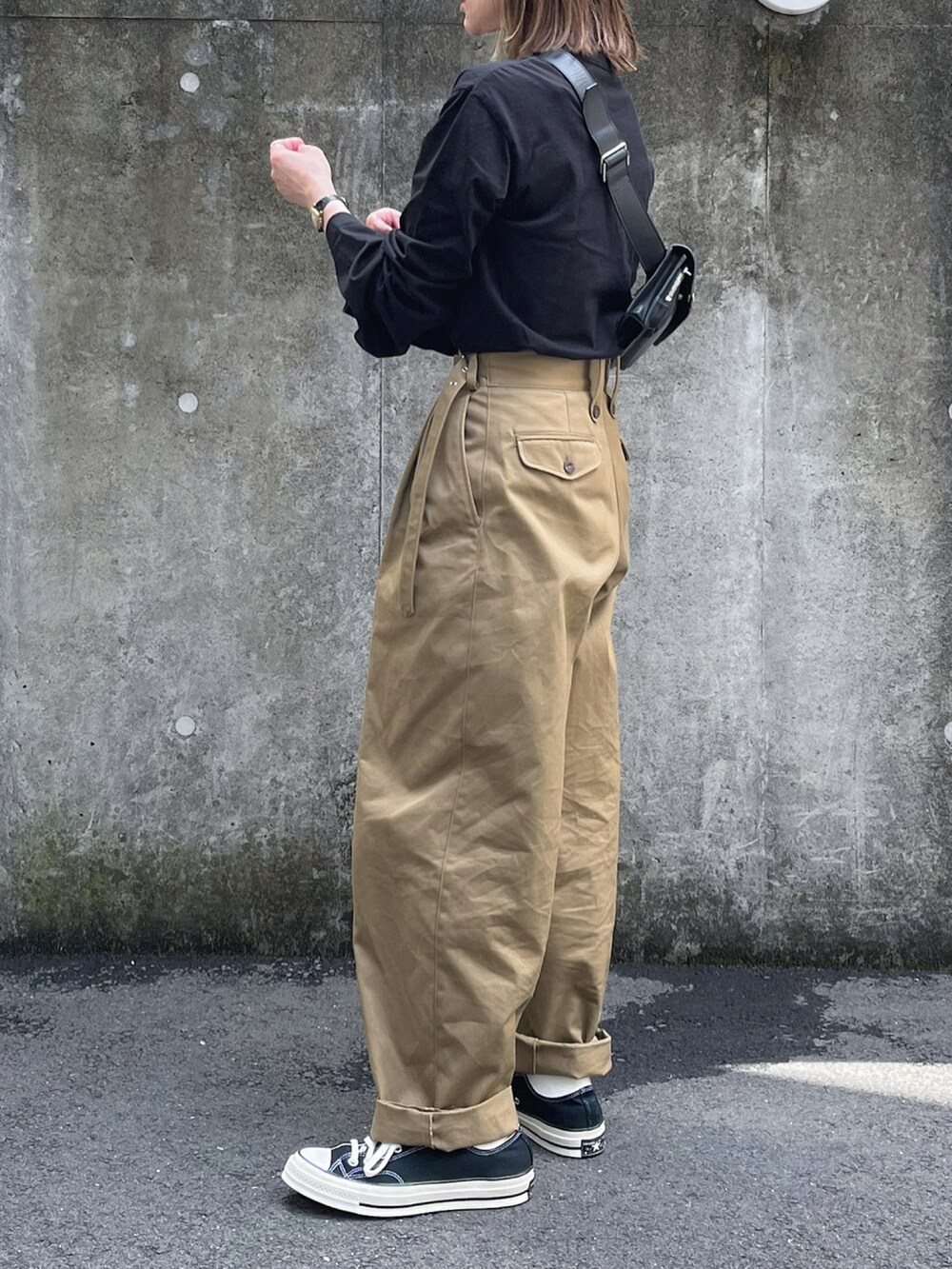 ブラック系のTシャツ/カットソー、ベージュ系のチノパンツ、ブラック系のボディバッグ/ウエストポーチを着用したレディースの春コーディネートの2枚目の写真