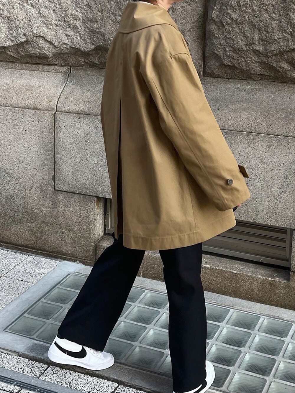 ブラウン系のステンカラーコート、ブラック系のニット/セーターを着用したレディースの冬コーディネートの4枚目の写真