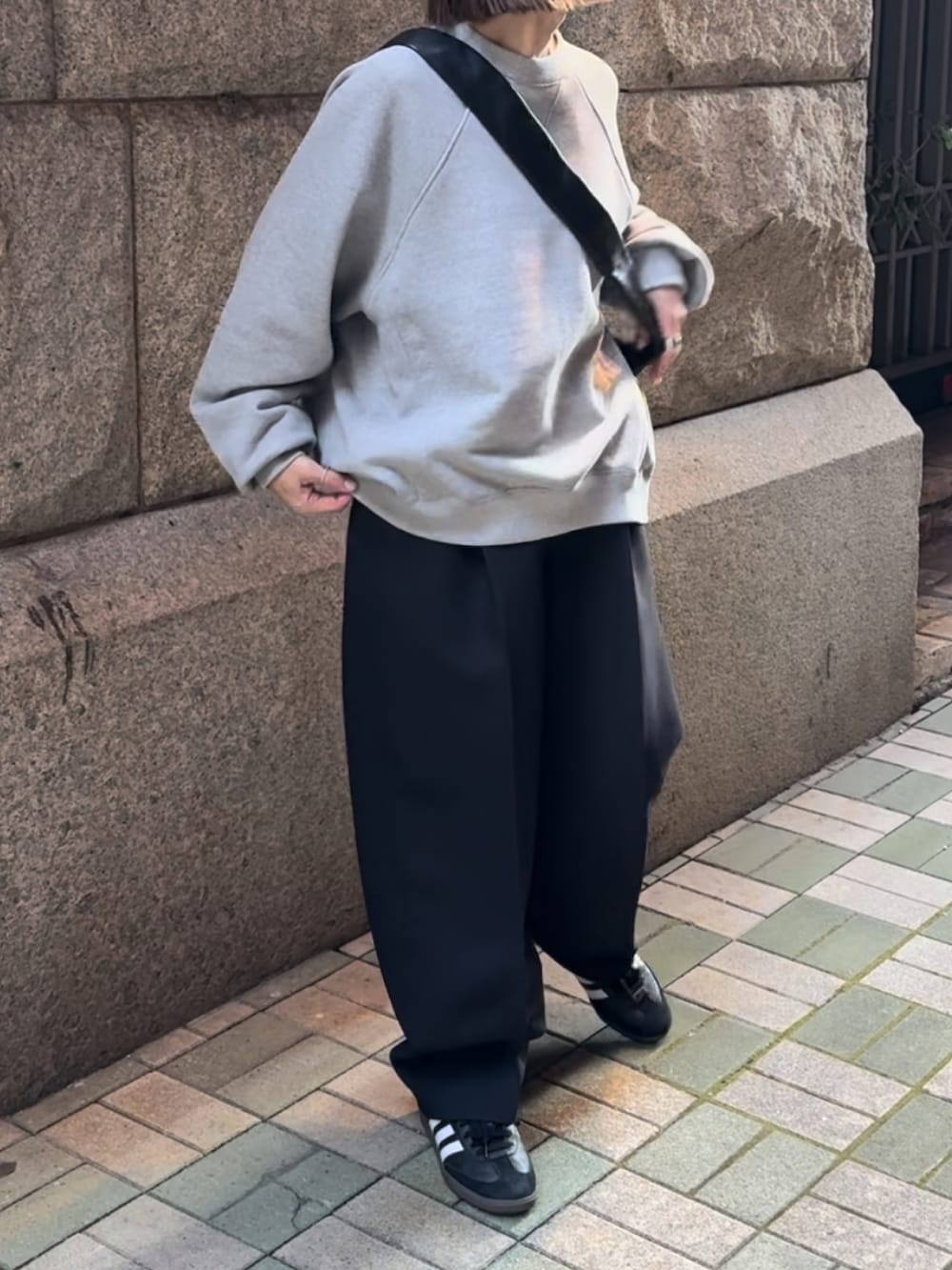 グレー系のスウェット、ブラック系のショルダーバッグ、ブラック系のスニーカーを着用したレディースの冬コーディネートの3枚目の写真