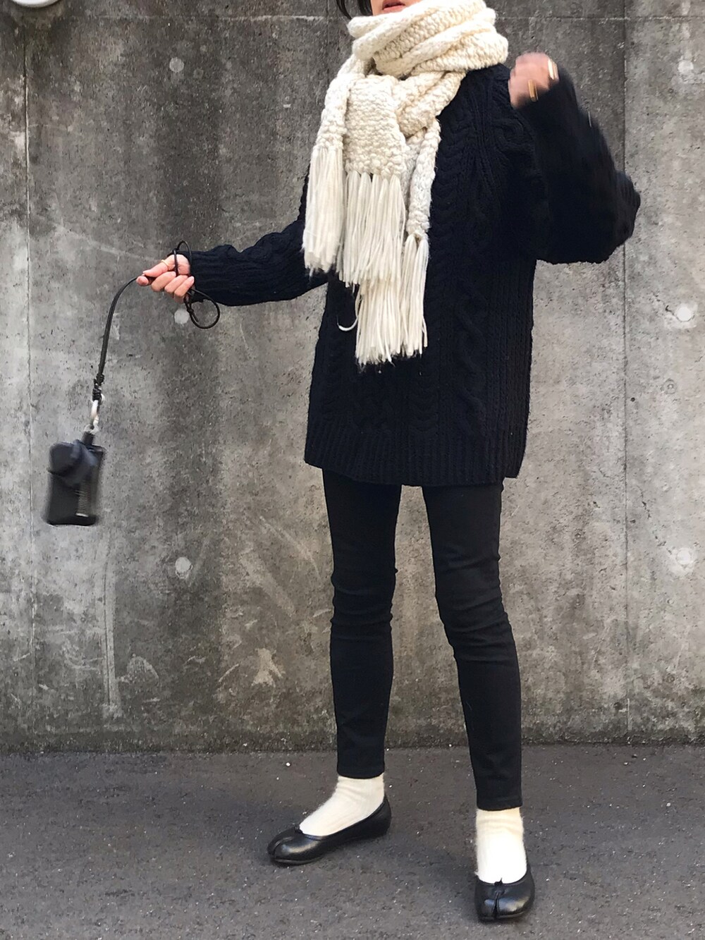 ブラック系のニット/セーター、ブラック系のバレエシューズ、ホワイト系のマフラーを着用したレディースの冬コーディネートの2枚目の写真