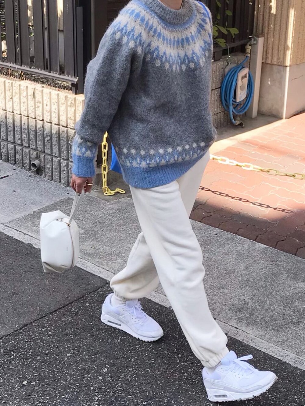 グレー系のニット/セーター、ホワイト系のショルダーバッグ、ホワイト系のスウェットパンツを着用したレディースの春コーディネートの2枚目の写真