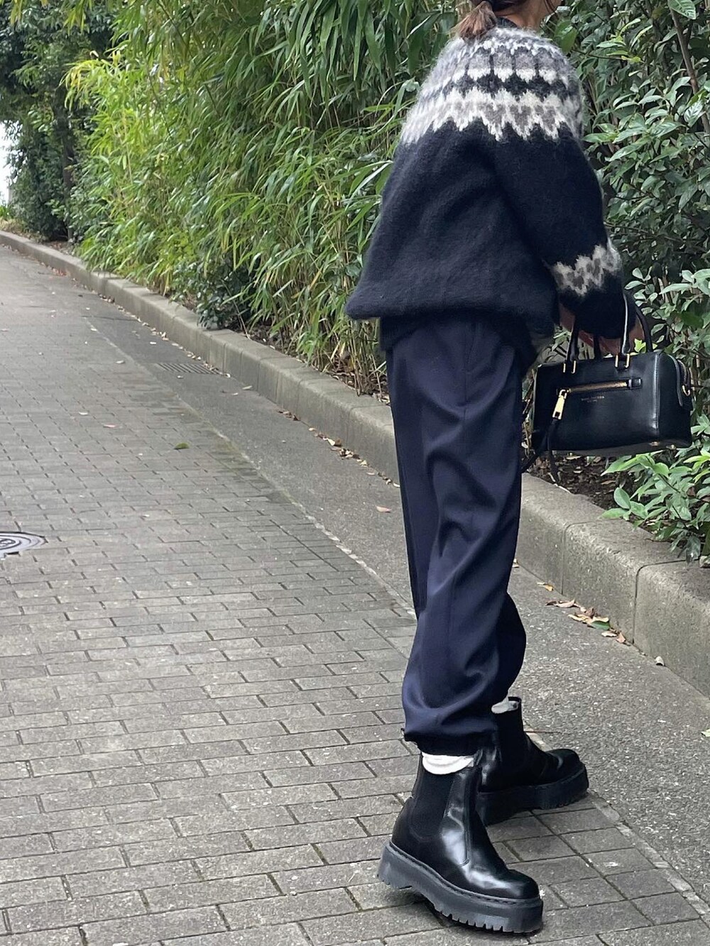 ブラック系のニット/セーター、ブルー系のスラックスを着用したレディースの秋コーディネートの3枚目の写真