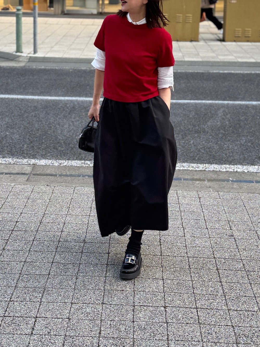 レッド系のニット/セーター、ブラック系のスカートを着用したレディースの冬コーディネートの2枚目の写真