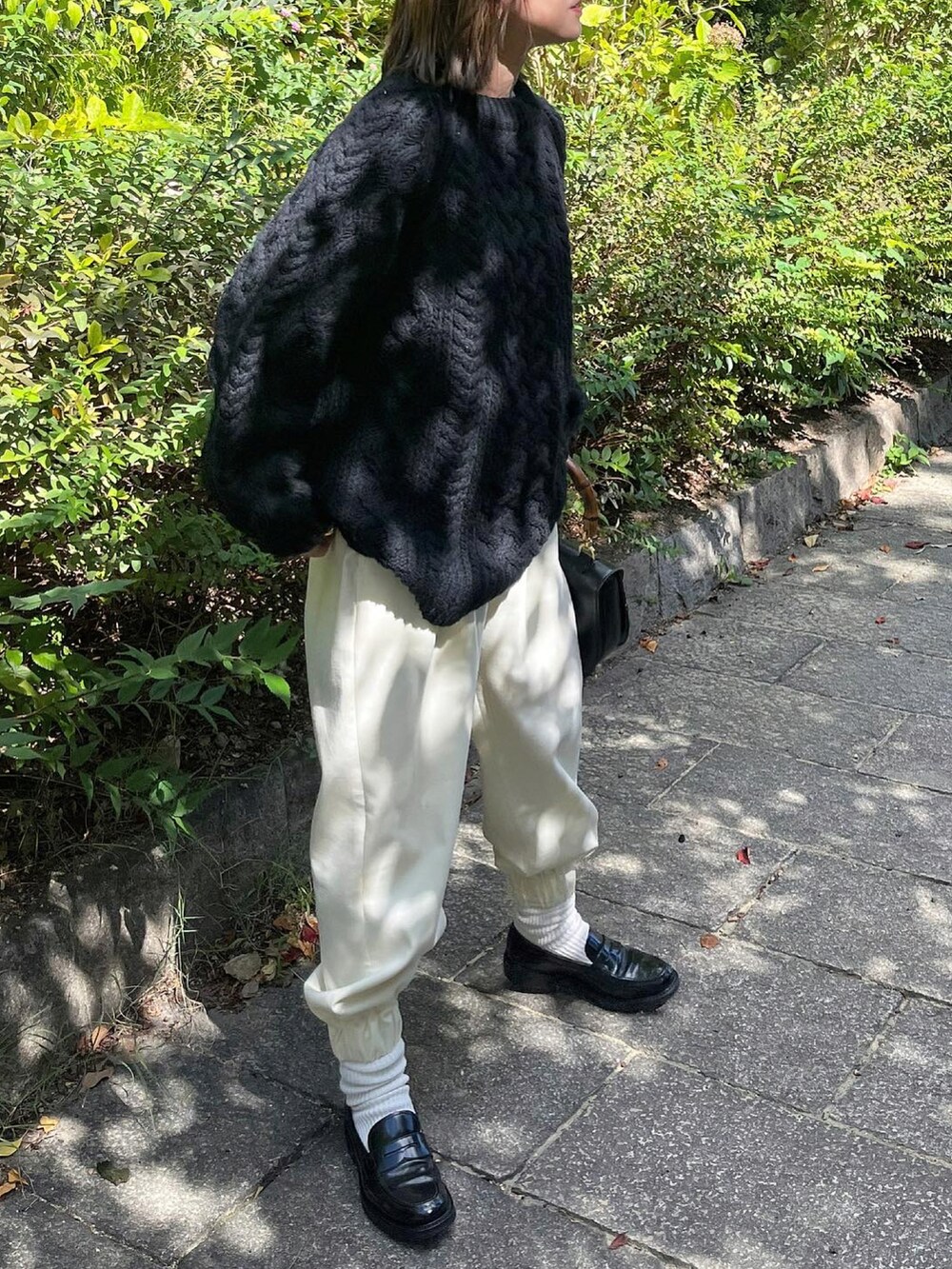 ブラック系のニット/セーター、ホワイト系のパンツ、ブラック系のローファーを着用したレディースの秋コーディネートの4枚目の写真