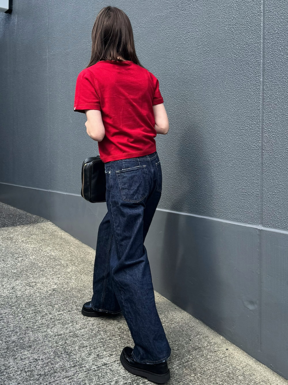 レッド系のニット/セーター、ブルー系のデニムパンツを着用したレディースの春コーディネートの4枚目の写真