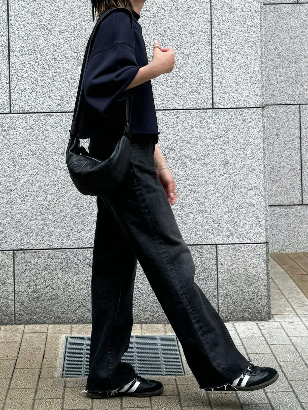 ブラック系のデニムパンツ、ブラック系のTシャツ/カットソー、ブラック系のスニーカーを着用したレディースの春コーディネートの4枚目の写真