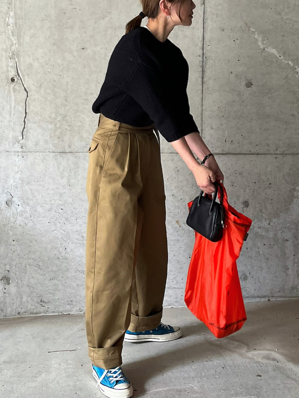 ベージュ系のチノパンツ、オレンジ系のエコバッグ/サブバッグ、ブラック系のボストンバッグを着用したレディースの冬コーディネートの4枚目の写真